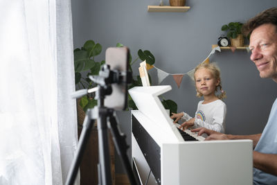 Father and daughter learning to play piano through mobile phone at home