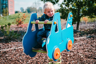 Blond young toddler boy playing at children playground.