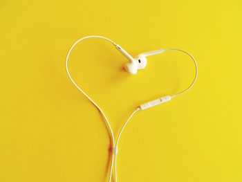 Heart shape formed of headphones over yellow background