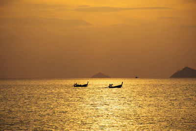 Silhouette people on sea against sky during sunset