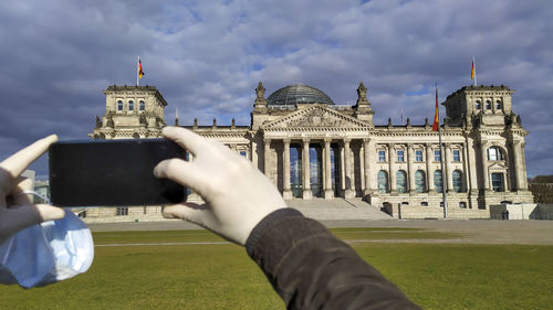 Cropped image of people photographing in city against sky