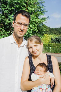 Portrait of parents with baby daughter standing in park