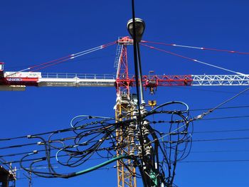 Low angle view of electricity pylon against blue sky