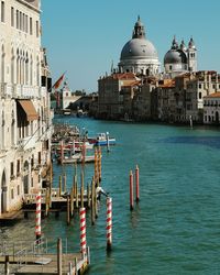 Boats moored in canal by buildings against sky