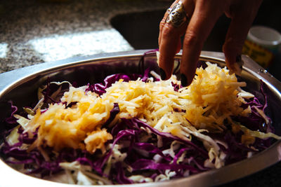 Close-up of hand preparing salad in plate
