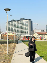 Portrait of young man standing on field against clear sky