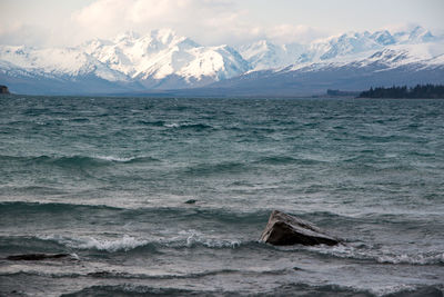 Scenic view of sea and snowcapped mountains against sky