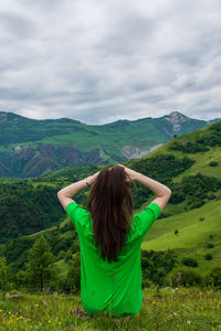 Rear view of woman standing on landscape against mountain range