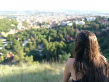 Rear view of woman sitting against landscape