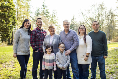 Family of eight posing for photo in park.