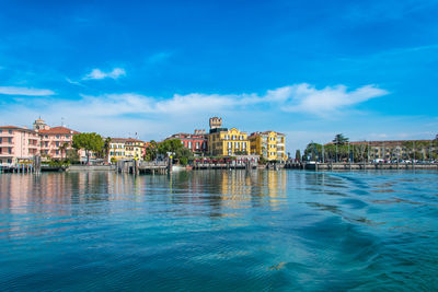 View of city at waterfront against cloudy sky