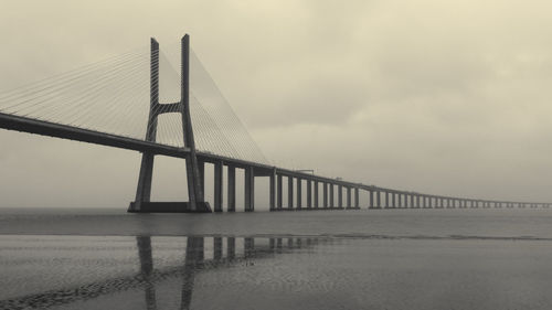 Low angle view of suspension bridge against cloudy sky