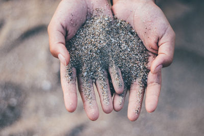 Close-up of child hand holding sand at beach