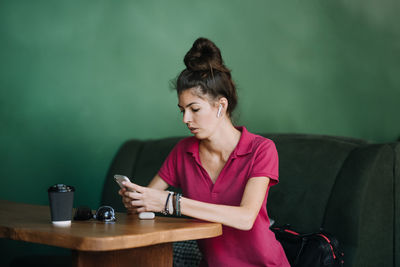 Young woman looking down while sitting on table