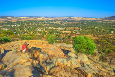 High angle view of woman photographing crouching on rocks