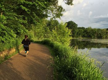 Full length of woman running on road by lake