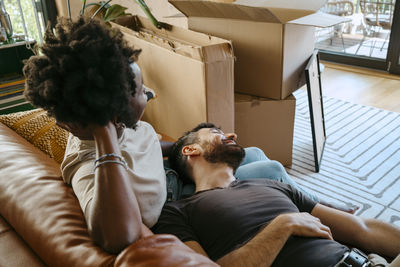 Multiracial couple relaxing together on sofa in living room at new home