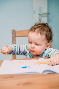 Portrait of cute boy holding pencil at home