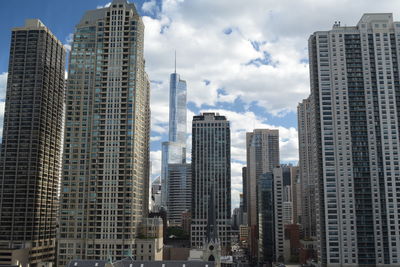 Low angle view of modern buildings against cloudy sky