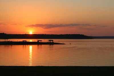 Silhouette boats in sea against orange sky