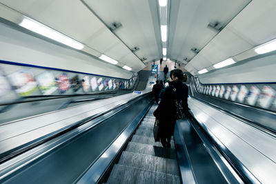 Rear view of people on escalators at subway station