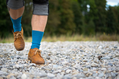 Low section of man walking on pebbles at beach