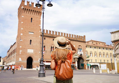 Cultural tourism in italy. rear view of female backpacker visiting medieval town of ferrara, italy