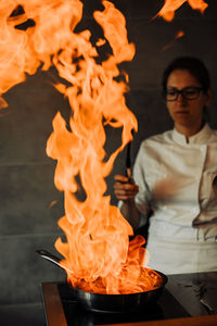 Female chef is making flambé in the restaurant kitchen