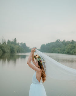 Woman standing by tree against sky