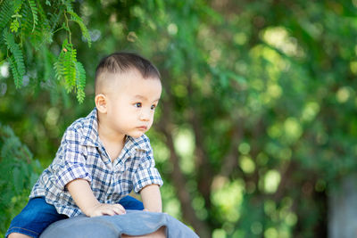 Cute boy looking away while sitting outdoors