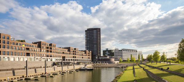 City at waterfront against cloudy sky