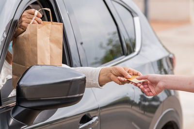 Midsection of woman holding hands on car