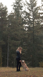 Rear view of woman with dog in the forest