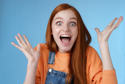 Portrait of happy young woman against blue background