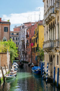 Boats moored in canal amidst buildings