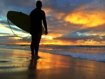 Silhouette of people on beach at sunset