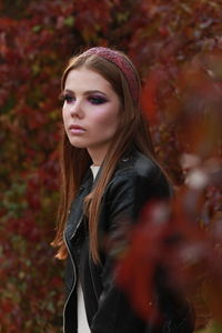 Young woman wearing leather jacket while standing in forest