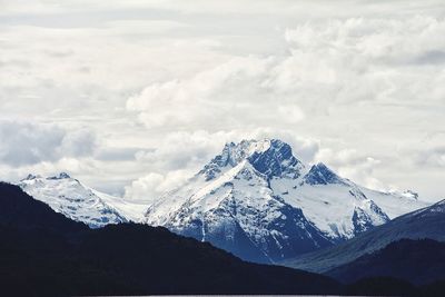 Scenic view of snow covered mountains against cloudy sky