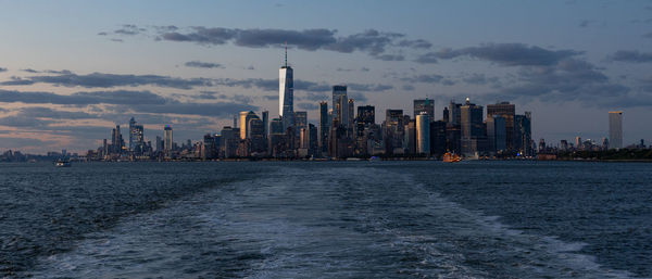 Lower manhattan skyline at sunset viewed from the water.