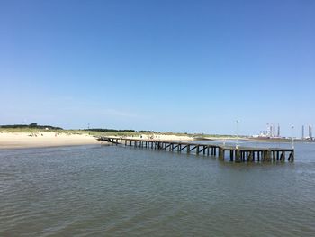 Pier over sea against clear blue sky