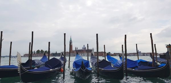 Boats moored in canal against sky