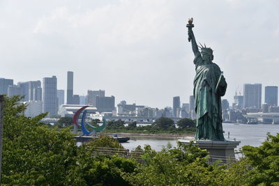 Statue in city against sky