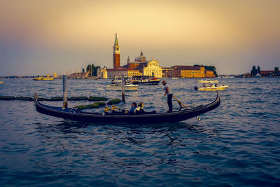 People traveling in gondola against church of san giorgio maggiore