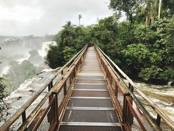 Footbridge over river against sky