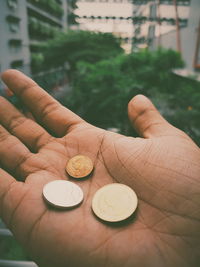 Close-up of hand holding coins outdoors