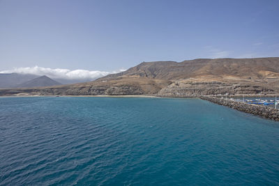 Scenic view of sea and mountains against blue sky