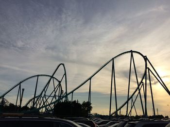 Low angle view of silhouette rollercoaster against cloudy sky during sunset