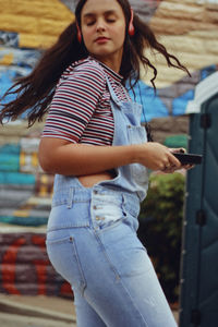 Teenage girl tossing hair while listening to music on headphones