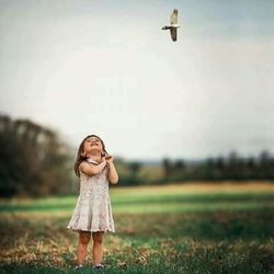 Happy boy standing on grass against sky