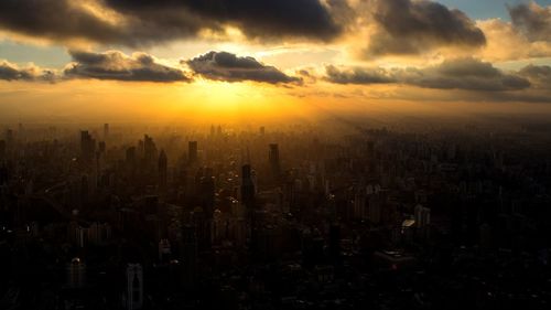 View of city against cloudy sky during sunset